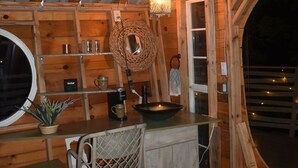 Ein gemütliches Blockhaus-Interieur mit Holzausstattung, einem Rundfenster, einer kleinen Küchenzeile mit Spüle und einer Pendelleuchte.