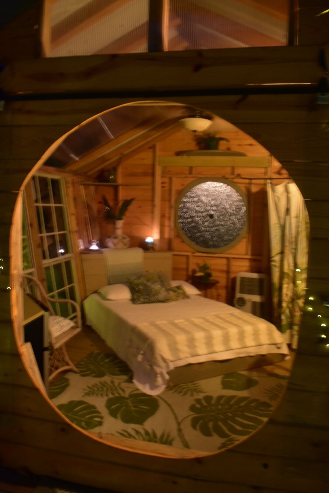A cozy, circular wooden room with a bed, a small table, and a chair.