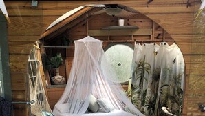 Ein gemütlicher, kreisförmiger Holzraum mit Bett, Hängematte und kleinem Tisch mit Pflanze.