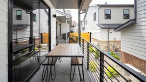 A covered outdoor patio with a wooden table and benches, surrounded by white siding houses. - 5-minute walk to downtown!   27-day minimum rental.  (Bozeman)