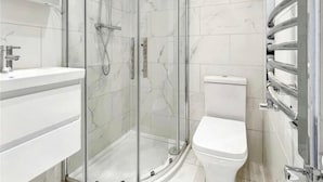 A modern bathroom with a glass-enclosed shower, a white toilet, and a vanity with a mirror.