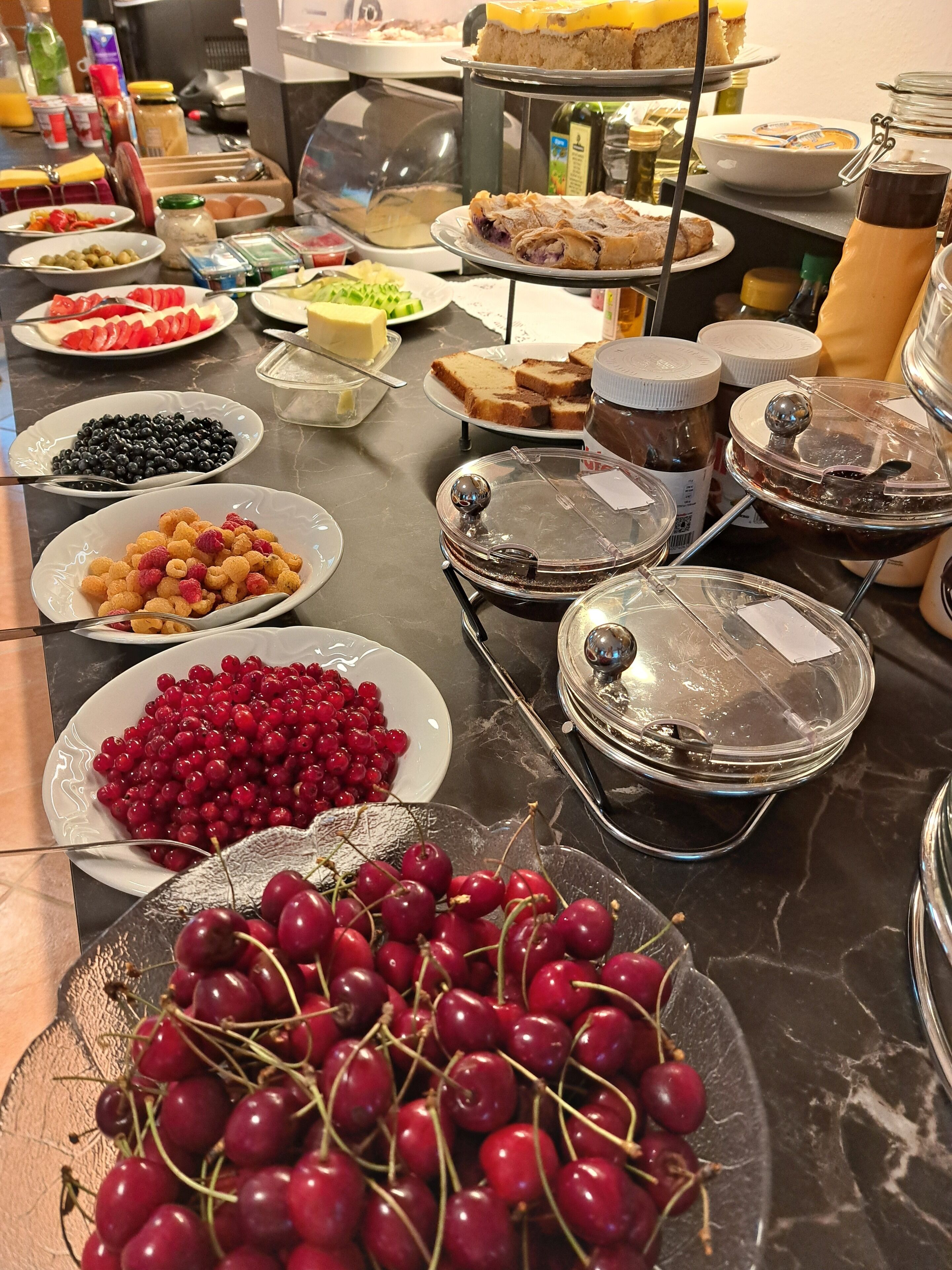 A buffet with various food items including fruits, pastries, and spreads.