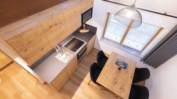 A modern kitchen with wooden cabinetry, a built-in microwave, and a dining area with a wooden table and black chairs.