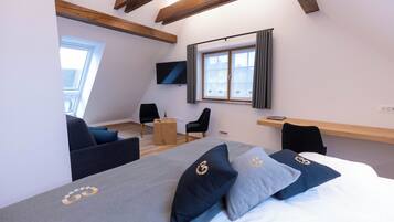 Een moderne hotelkamer met een groot bed, een tv aan de muur, een klein houten tafeltje en een raam met gordijnen.
