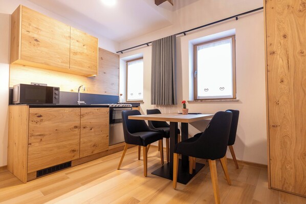 A compact kitchen with wooden cabinets, a black countertop, and a dining area with a table and chairs.