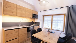 A modern kitchen with wooden cabinets, a microwave, and a dining area with a table and chairs. - Hotel Vila Loka (Skofja Loka)