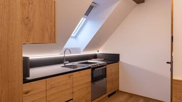 A modern kitchen with wooden cabinetry, a black countertop, and a skylight.