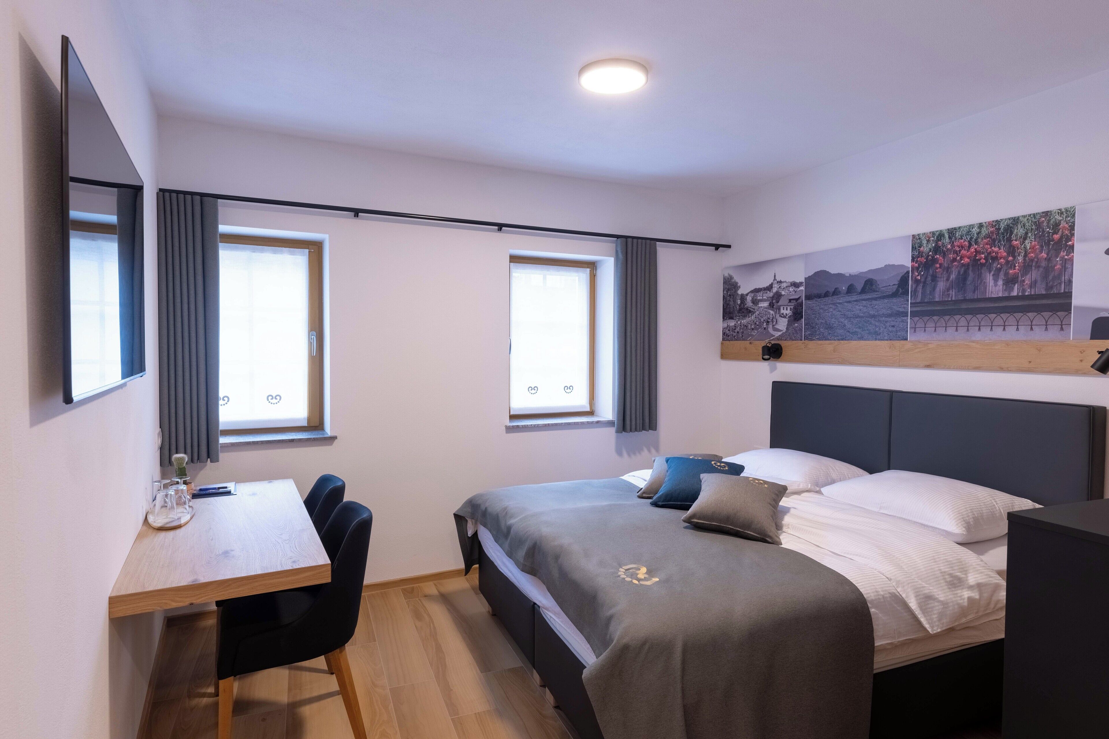 Ein modernes Hotelzimmer mit einem Bett, einem Schreibtisch und zwei Fenstern.