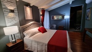 A hotel room with a bed, a nightstand, a lamp, a chair, a mirror, and a view of the outside. - Vi Ja Villa Janas  (Sestu)