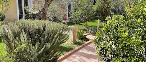 A garden pathway leading to a stone building with a door and windows.