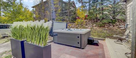 Eine Terrasse mit Whirlpool, Sitzgelegenheiten und einem Pflanzkübel mit hohen Gräsern.