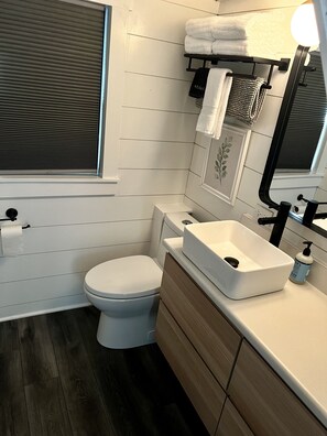 A modern bathroom with a toilet, sink, and window.