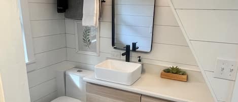 Ein modernes Badezimmer mit Toilette, Waschbecken mit Spiegel und Holzschränken.