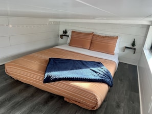 Una cama bien hecha con ropa de cama a rayas, un plaid azul oscuro y almohadas a juego.