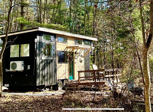 A mobile home with a small porch and a window overlooking a wooded area.