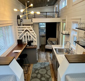 A compact kitchen with a central island, a dining area with a bench, and a small seating area with a chair.