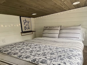 Ein Schlafzimmer mit einem Bett, einer an der Wand befestigten Ablage mit einem Schild und Lichterketten.