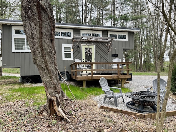 A mobile home with a deck, outdoor seating, and a fire pit.