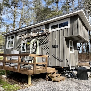 Eine kleine Holzhütte mit einer Terrasse, einer Veranda und einer Einfahrt mit Kies.