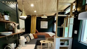 A compact kitchen with a sink, stove, and dining area. - Dahlia Tiny House by the Lake (Logan)