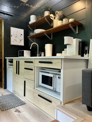 Cocina moderna con microondas, horno y armarios de madera.