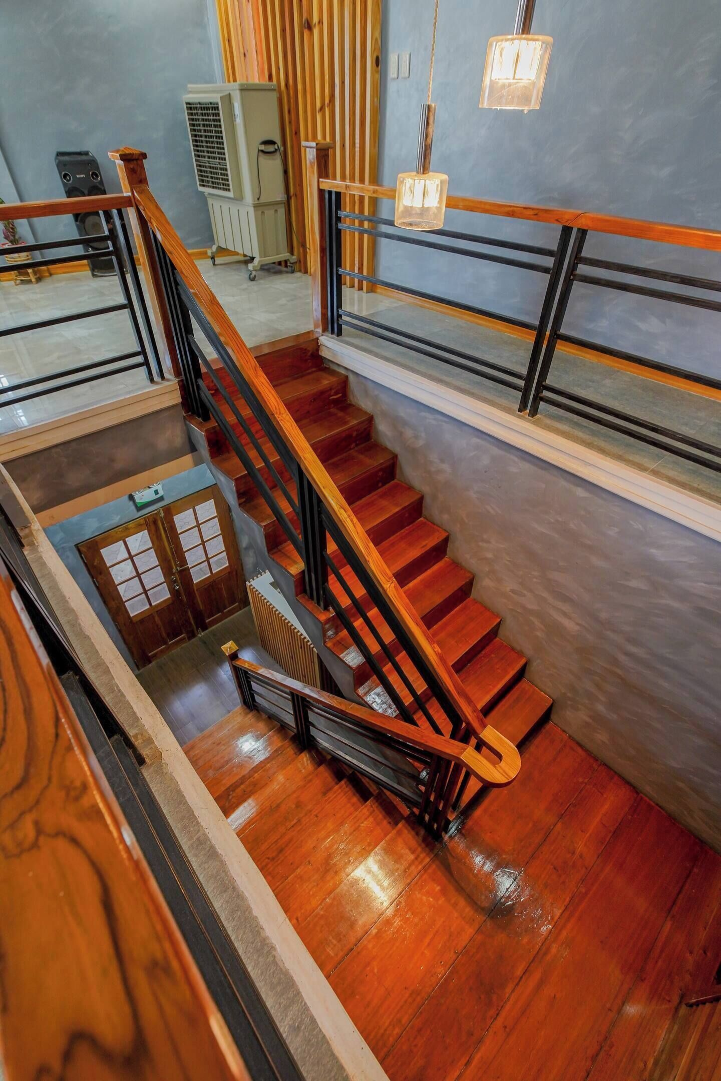 A wooden staircase with a metal railing, leading to a landing with a door and a radiator.