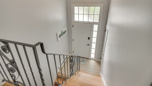 A staircase with a metal railing leading to a door with a frosted glass window. - Middletown Vacation Rental: 2 Mi to Beach! (Middletown)