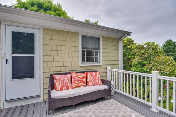 A covered porch with a wicker sofa, a white railing, and a window. - Middletown Vacation Rental: 2 Mi to Beach! (Middletown)