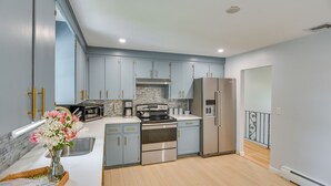 A modern kitchen with light blue cabinets, stainless steel appliances, and a wooden floor. - Middletown Vacation Rental: 2 Mi to Beach! (Middletown)