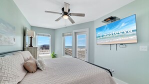 Une chambre avec un lit, un ventilateur de plafond, une télévision et une vue sur la plage.