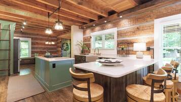 A kitchen with a central island, wooden ceiling, and bar stools.