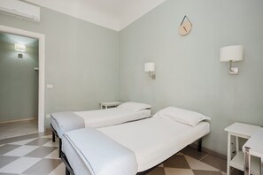 Una stanza con due letti, una sveglia appesa al muro e un tavolino.