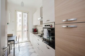Une cuisine moderne avec des armoires blanches, un four noir et un évier en acier inoxydable.