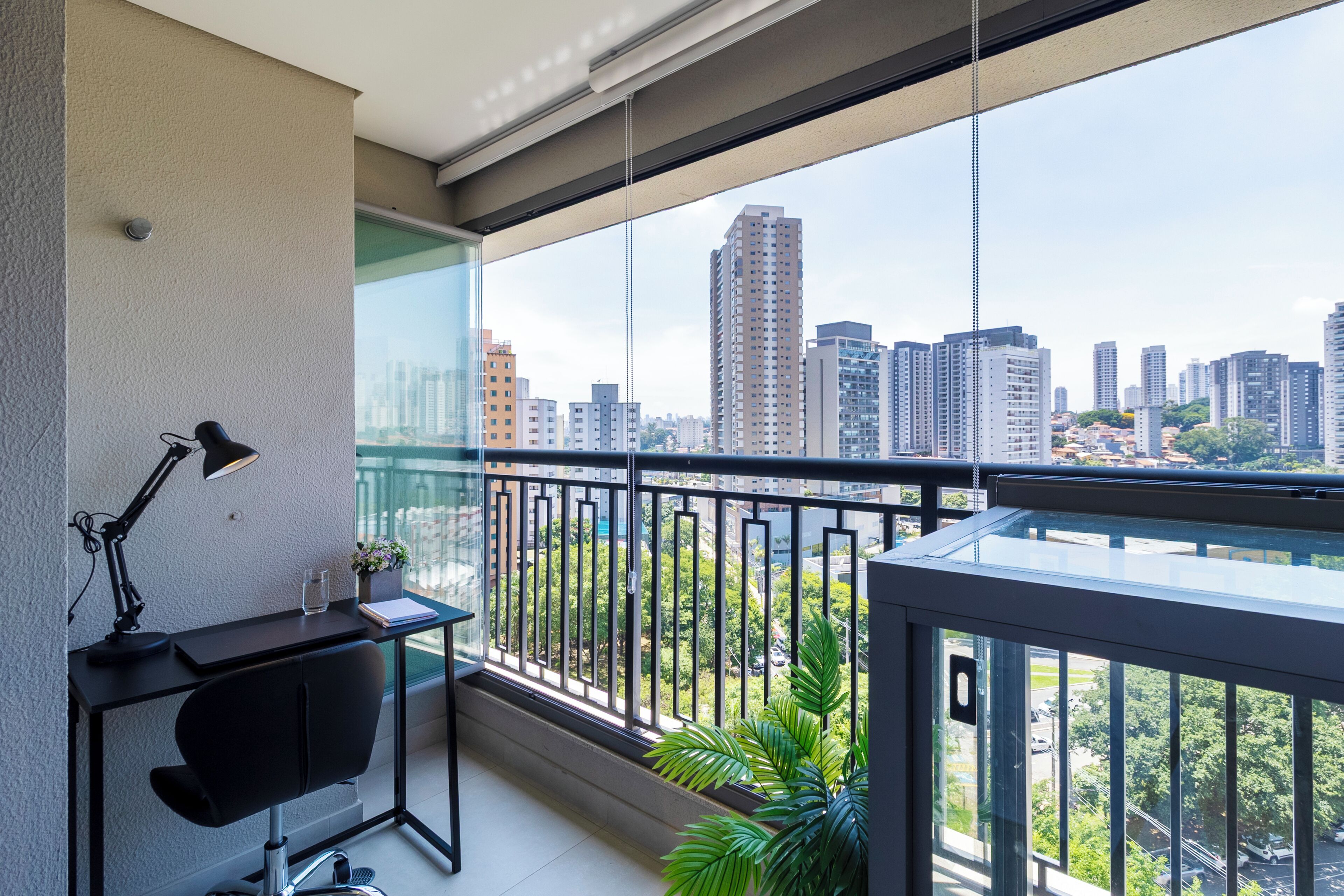 A balcony with a desk, chair, and potted plant.