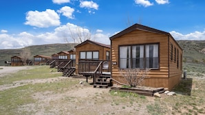 A row of wooden cabins with large windows and a staircase leading to the entrance. - Blue Mesa Recreational Ranch (Gunnison)