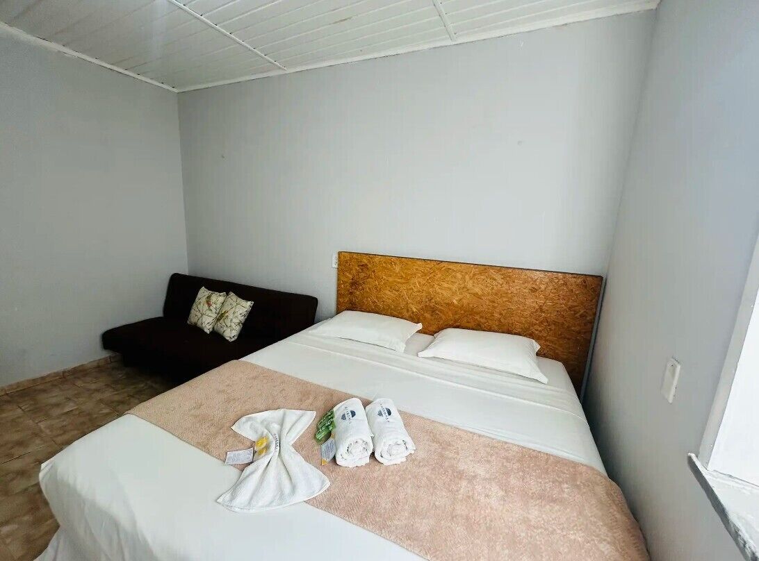 Habitació d'hotel amb un llit, un sofà de color fosc i un panell de fusta al capçal.