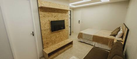 A bedroom with a built-in TV, a bed, a sofa, and a ceiling with skylights.