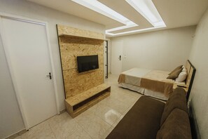 A bedroom with a built-in TV, a bed, a sofa, and a ceiling with skylights. - Pousada Mansomar (Jijoca de Jericoacoara)