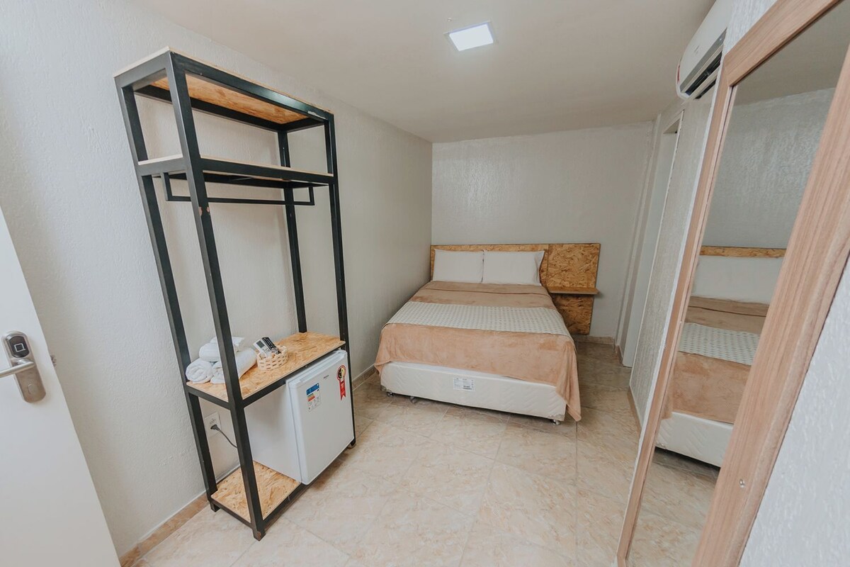 A compact room with a bunk bed, a small desk with a refrigerator, and a wardrobe.