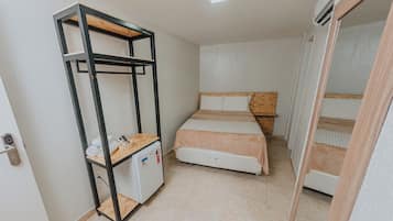 A compact room with a bunk bed, a small desk with a refrigerator, and a wardrobe.