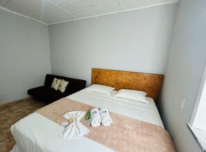 A hotel room with a bed, a dark-colored sofa, and a wooden headboard. - Pousada Mansomar (Jijoca de Jericoacoara)