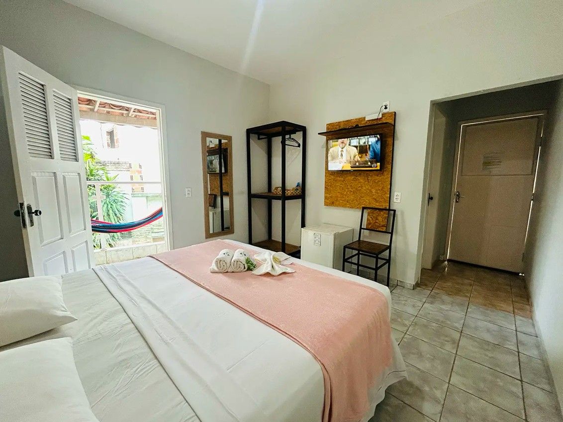 Ein Hotelzimmer mit Bett, Wandfernseher, Kleiderschrank und einer Tür zum Balkon.