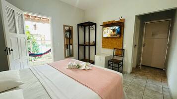 Ein Hotelzimmer mit Bett, Wandfernseher, Kleiderschrank und einer Tür zum Balkon.