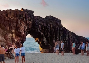 Una spiaggia con un arco naturale di roccia che sovrasta la sabbia.