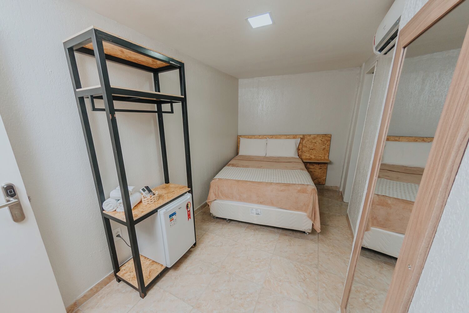 Habitació compacta amb un llit superposat, una taula petita amb nevera i un armari.