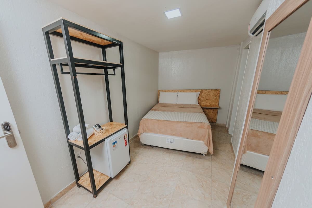 Habitació compacta amb un llit superposat, una taula petita amb nevera i un armari.