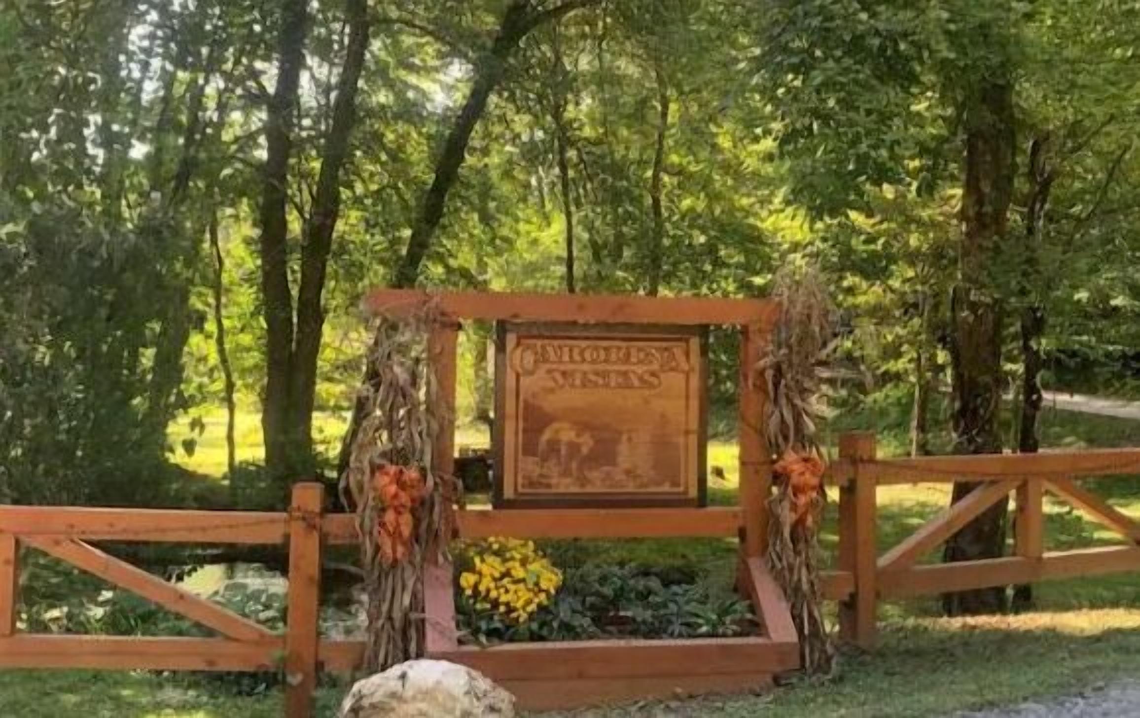 A wooden sign with the text "CULTURA VISTA" surrounded by a rustic fence and autumn leaves.
