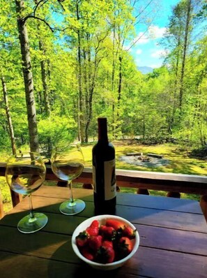 Ein Tisch mit einer Weinflasche, zwei Weingläsern und einer Schale Erdbeeren.