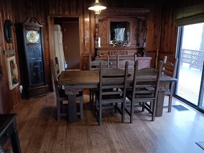 Un comedor de madera con una mesa grande y sillas, un reloj de pared y un espejo decorativo.