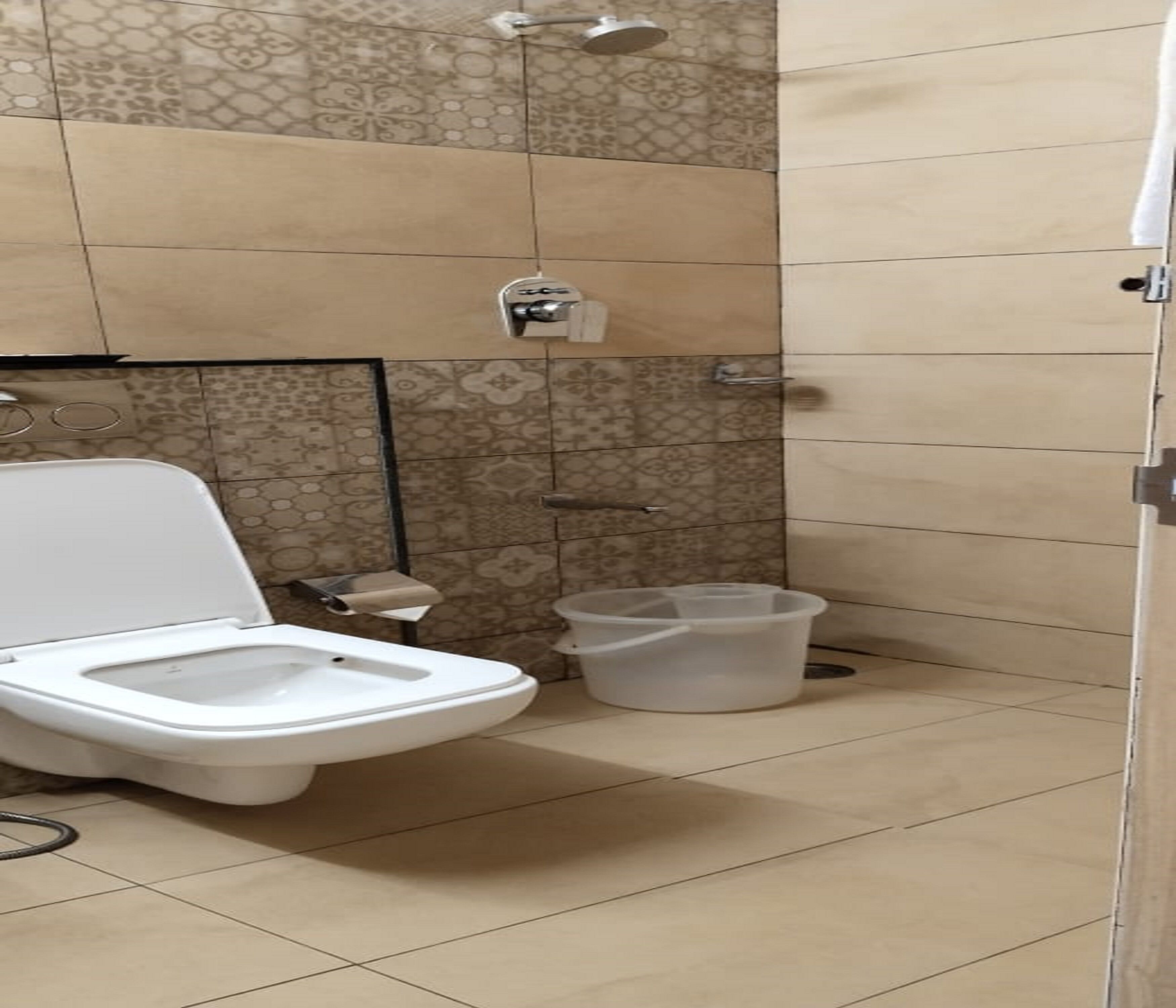 A bathroom with a toilet, a shower, and a trash bin.